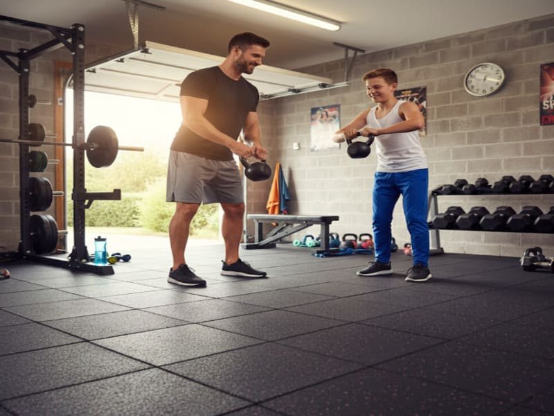 A clean and organized garage with black interlocking rubber floor tiles.